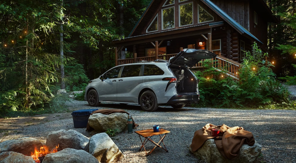 White 2025 Toyota Sienna with an open hatch parked by a house.