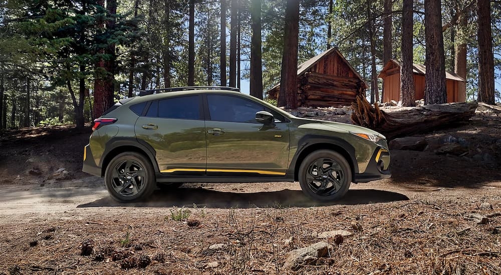 Side view of a green 2025 Subaru Crosstrek Sport parked in a forest.