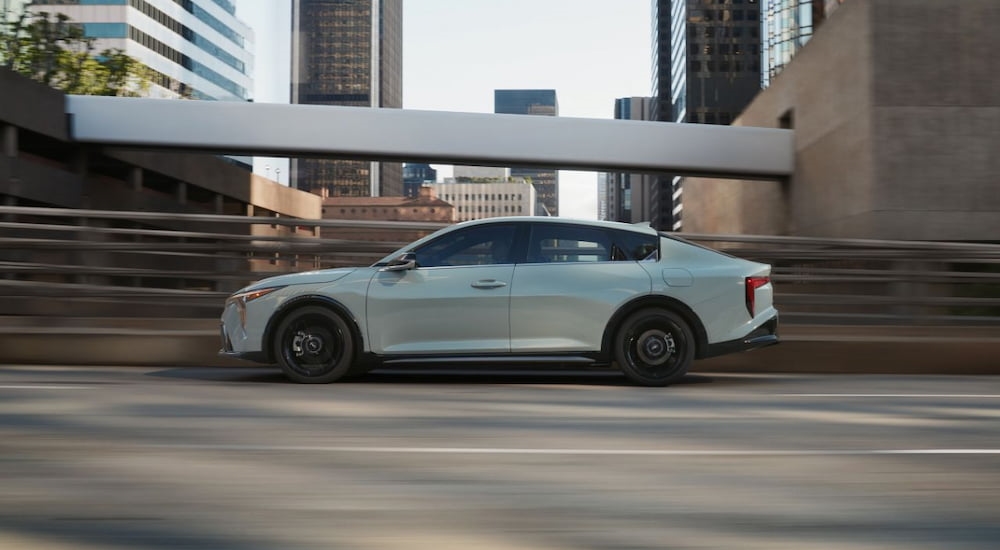 Side of a white 2025 Kia K4 driving on a bridge.