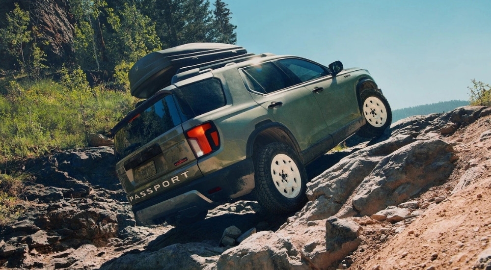 A green 2026 Honda Passport TrailSport Elite driving up a hill.