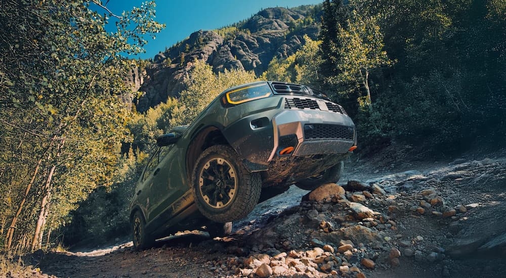 Green 2026 Honda Passport TrailSport driving up a steep hill.