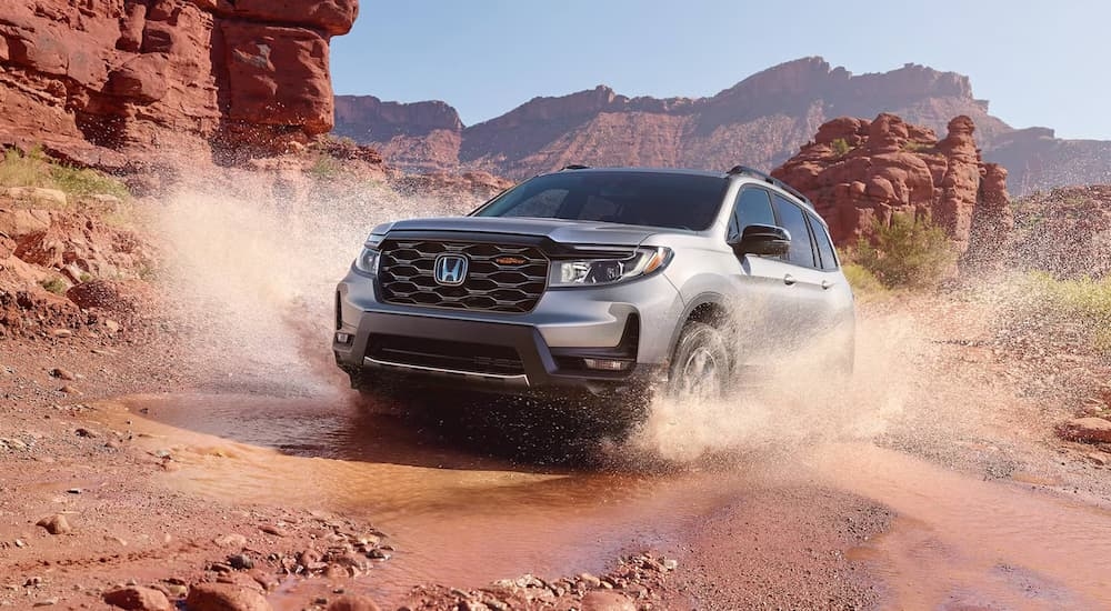 Silver 2026 Honda Passport TrailSport for sale driving through a puddle.