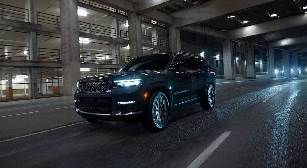 Black 2025 Jeep Grand Cherokee for sale in Rhinebeck driving under a bridge.