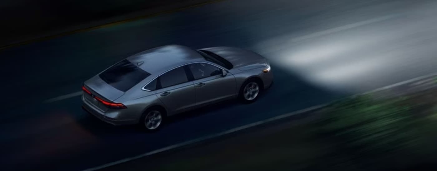 A silver 2025 Honda Accord for sale in Miami driving at night.