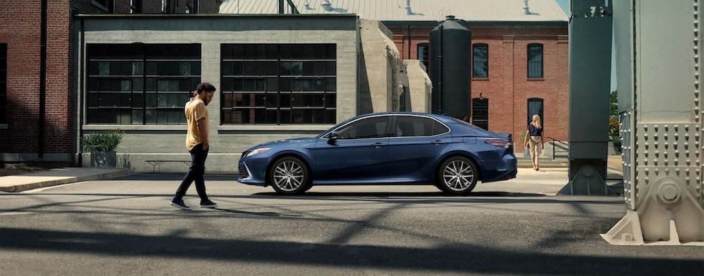 A blue 2024 Toyota Camry XLE parked in a city.