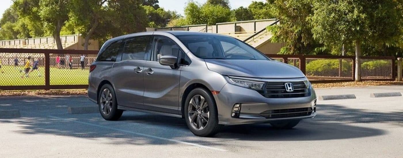 A silver 2024 Honda Odyssey parked near a soccer field.