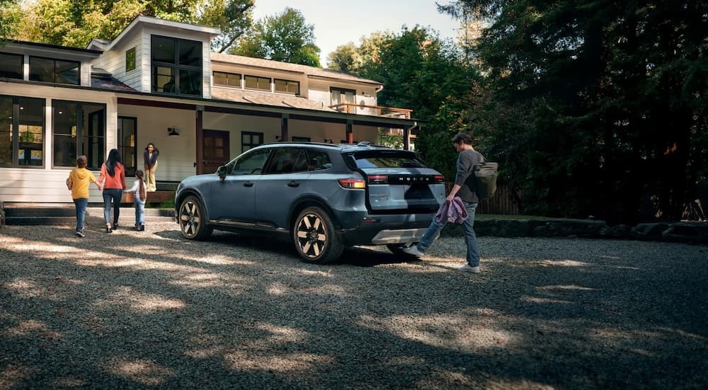 A family near a parked blue 2025 Honda Prologue for sale.
