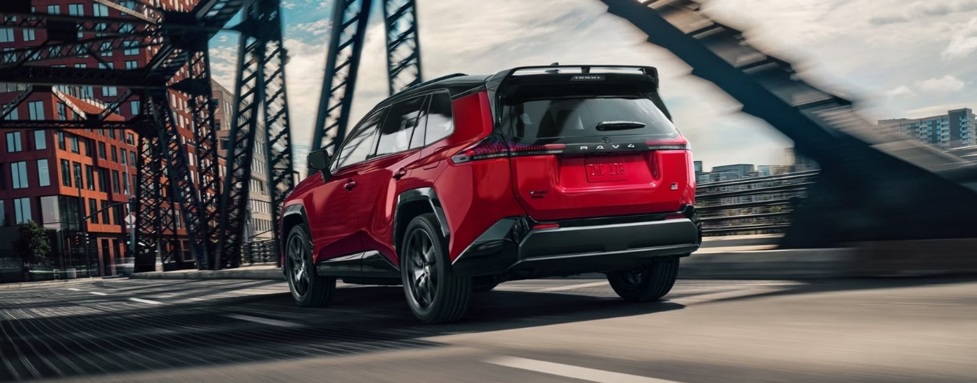 A red 2026 Toyota RAV4 PHEV GR Sport driving over a bridge.