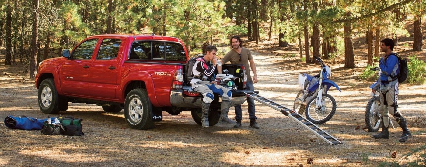 A red 2015 Toyota Tacoma for seal near White Plains parked near dirtbikes.