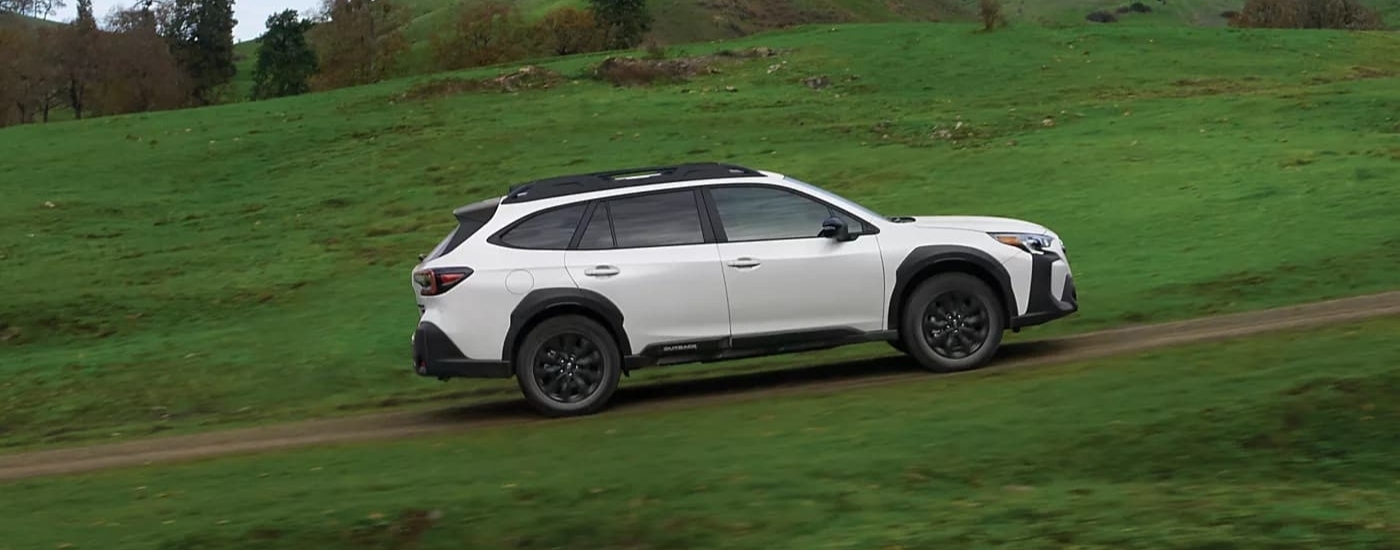 A white 2023 Subaru Outback Onyx driving to a Subaru dealer near Clinton Corners.