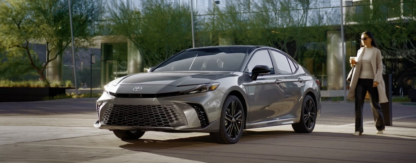 A person approaching a grey 2025 Toyota Camry for sale near Bennington.