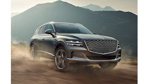 Genesis SUV driving on dirt road mountain landscape in background