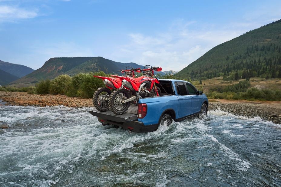 A Honda Ridgeline with two dirt bikes in the truck bed