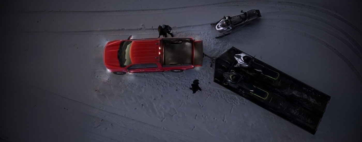 Snowmobiles near a red 2022 Ford F-150.