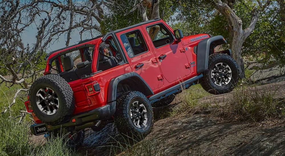 Red 2025 Jeep Wrangler Rubicon driving up a hill.