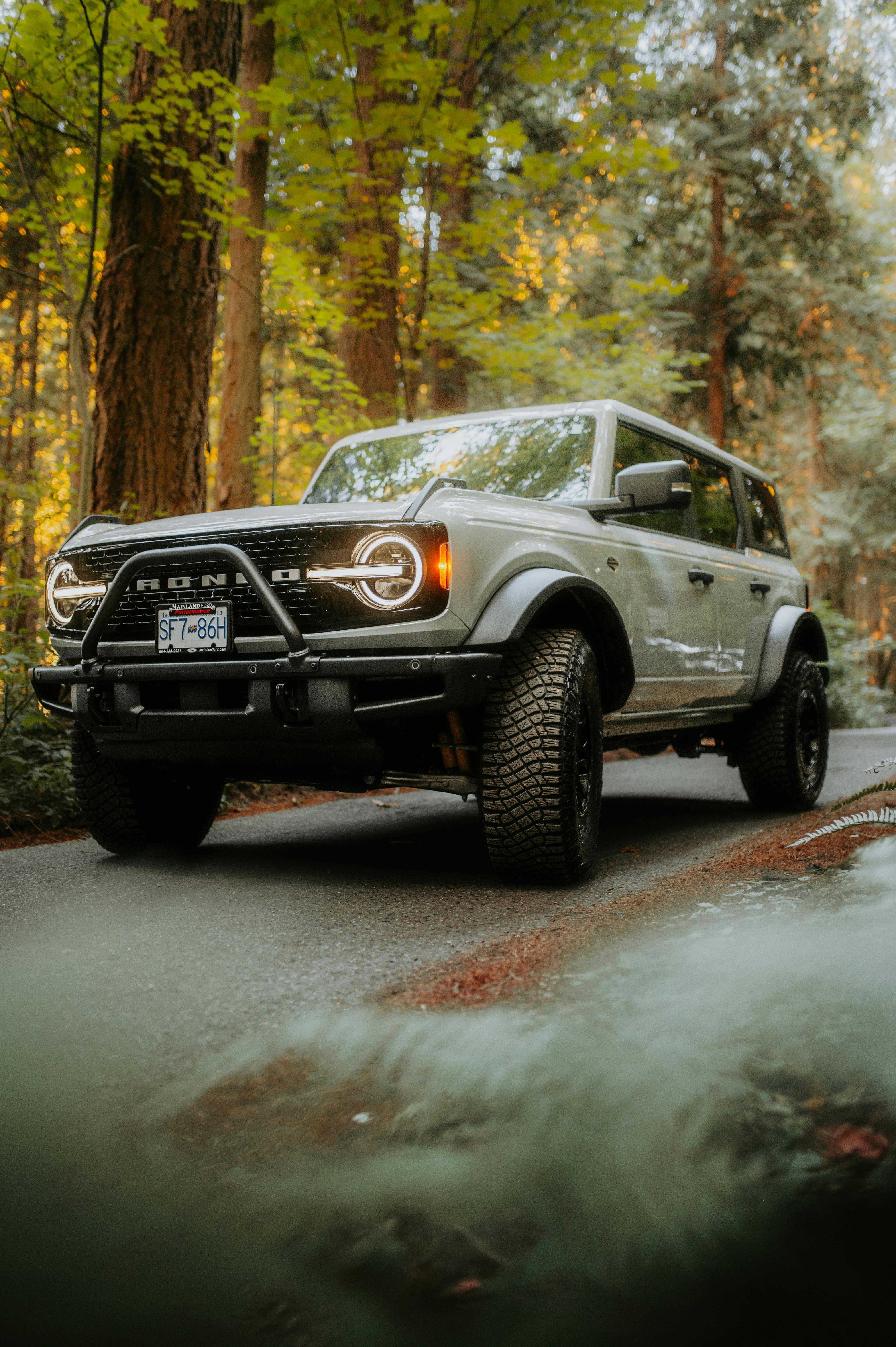 A Ford Bronco driving along a forested road