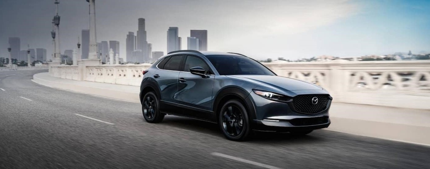 A blue Mazda CX-30 driving on a bridge.