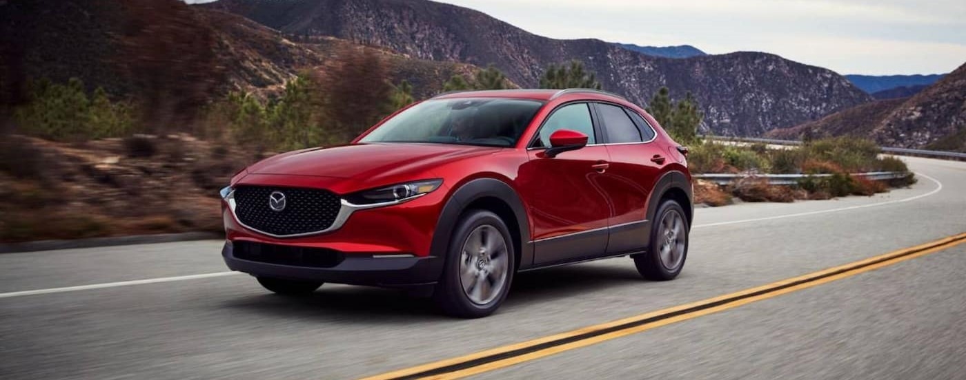A red 2025 Mazda CX-30 for sale near Hollywood is driving on a highway.