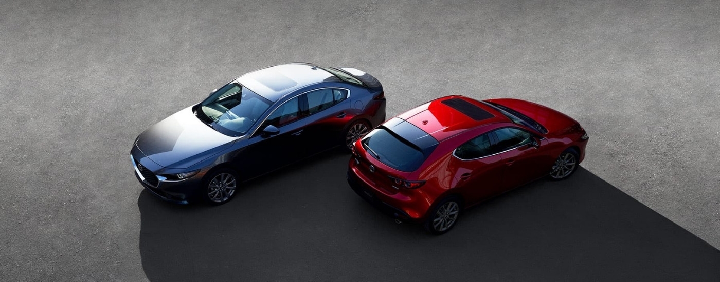 A grey and a red 2019 Mazda3 facing opposite directions.