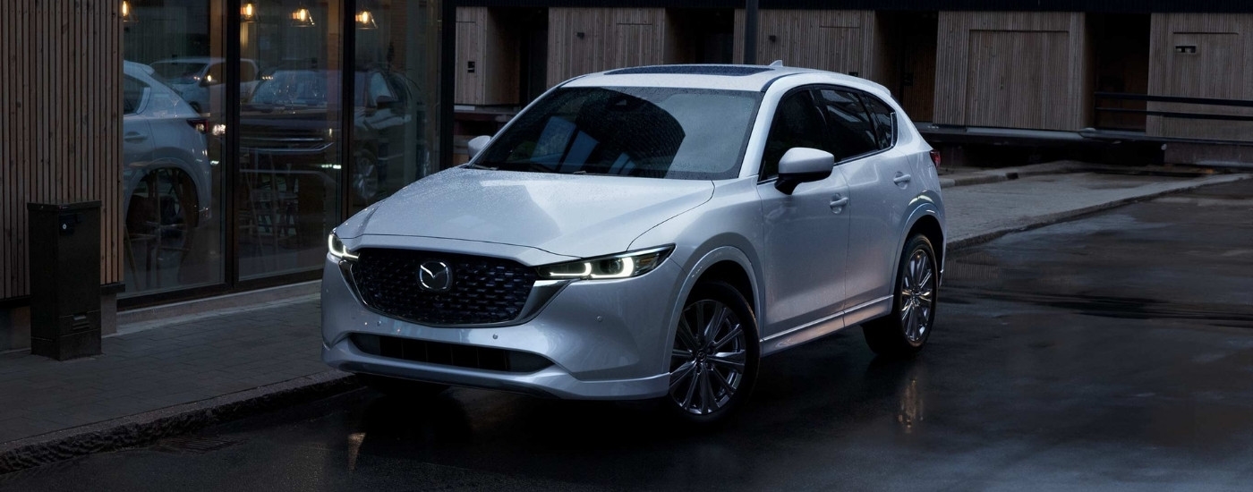 A white 2023 used Mazda CX-5 for sale near Hialeah parked in front of a shop.
