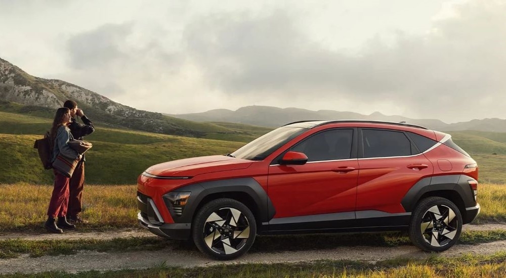 A red 2024 Hyundai Kona parked near hikers.