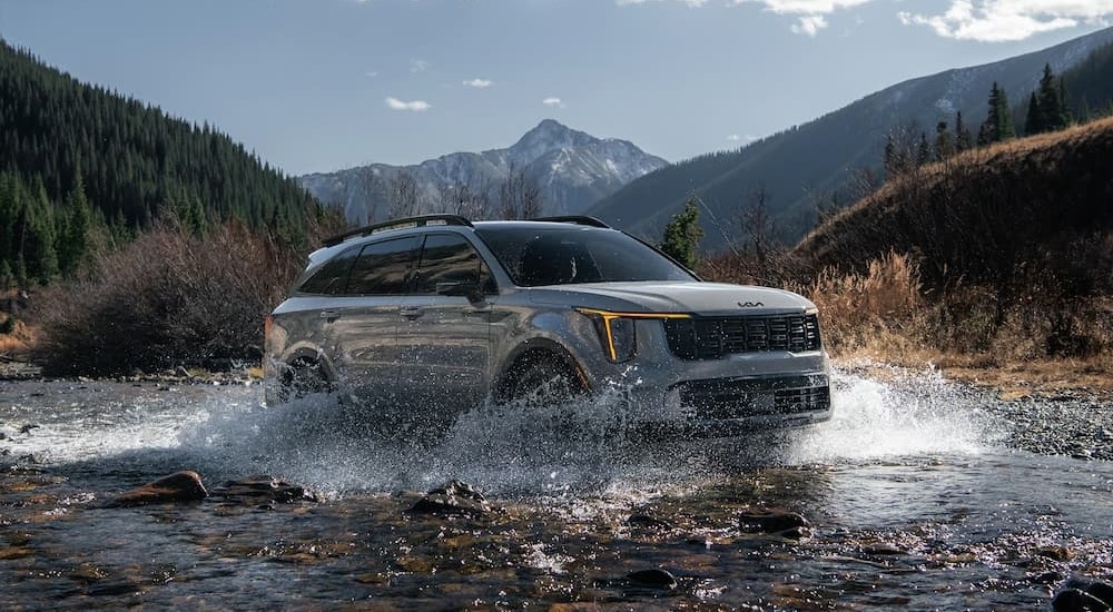 A gray 2025 Kia Sorento for sale driving through water.