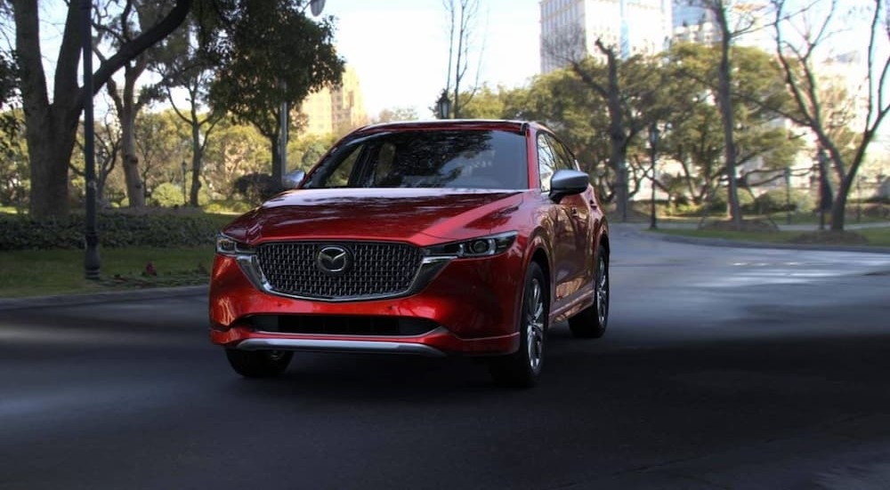 A red 2025 Mazda CX-5 driving in a city.