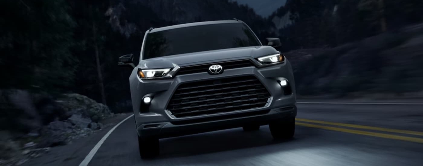 A silver 2025 Toyota Grand Highlander driving at night.