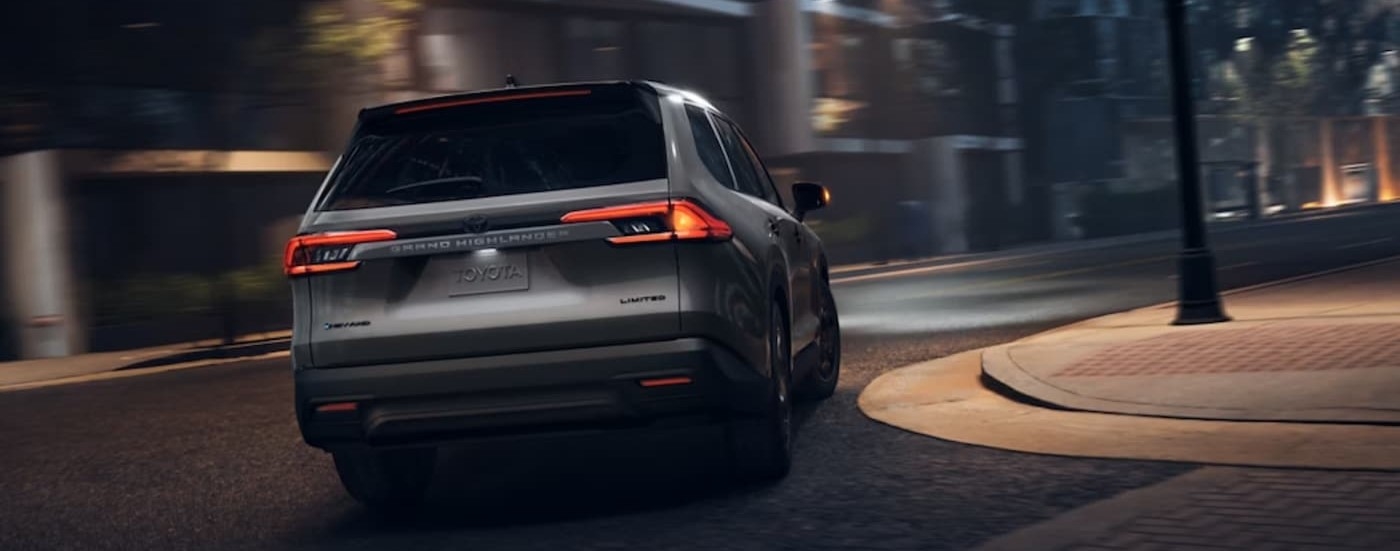 A silver 2025 Toyota Grand Highlander driving on a city street.
