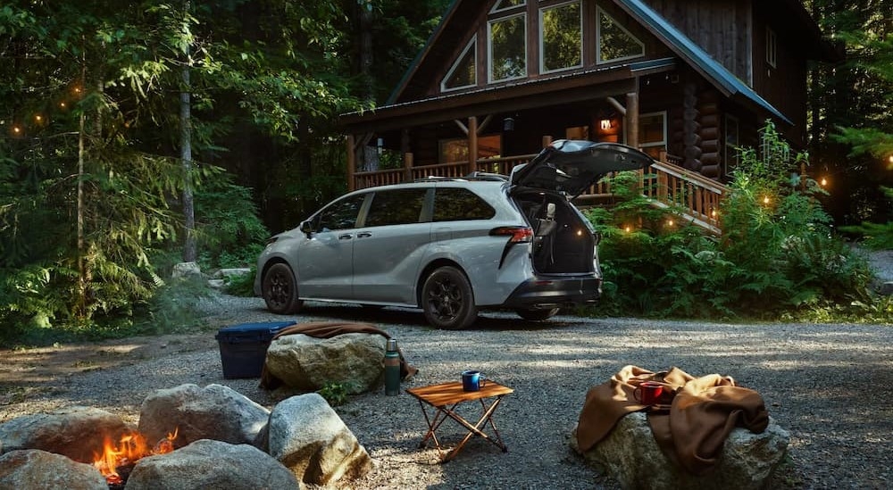 A blue 2025 Toyota Sienna parked near a log cabin.