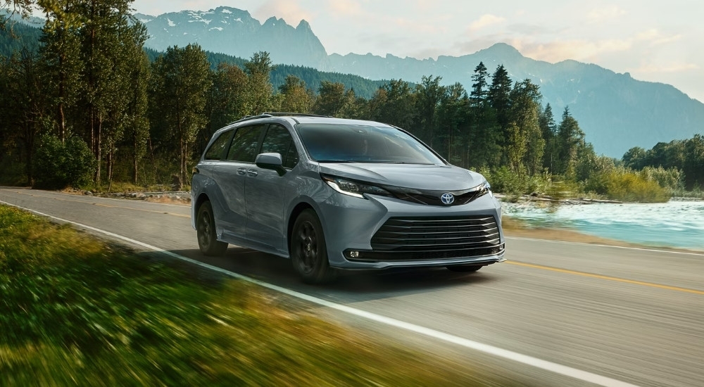 A grey 2025 Toyota Sienna Woodland Edition driving past a lake.