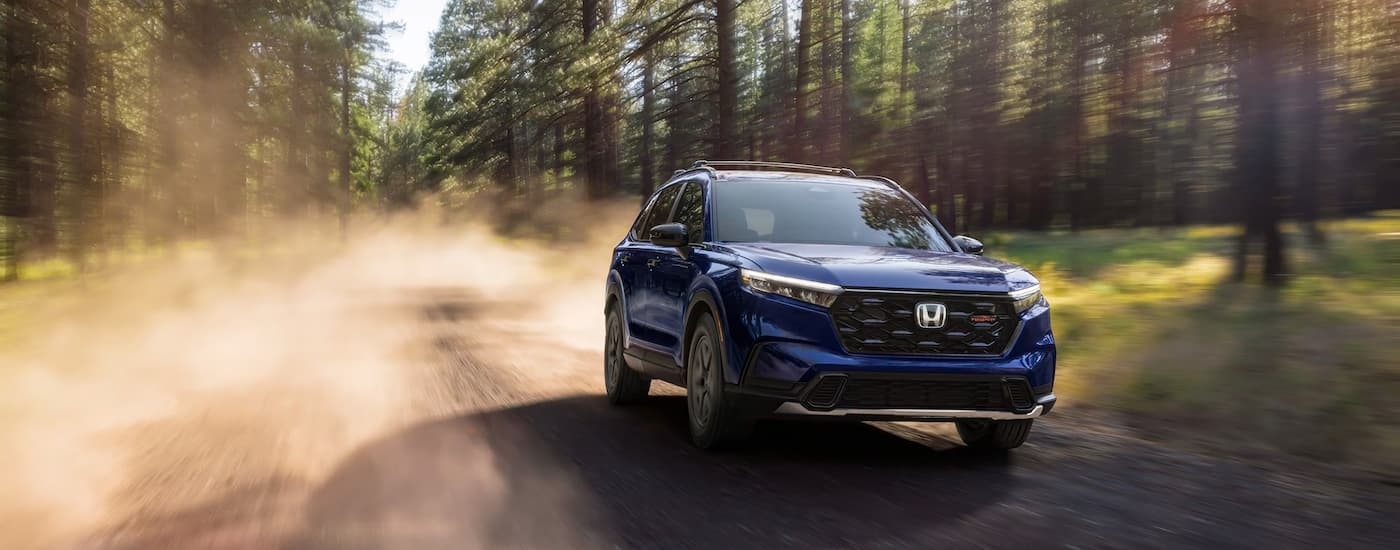Blue 2026 Honda CR-V Trailsport driving on a dirt road.