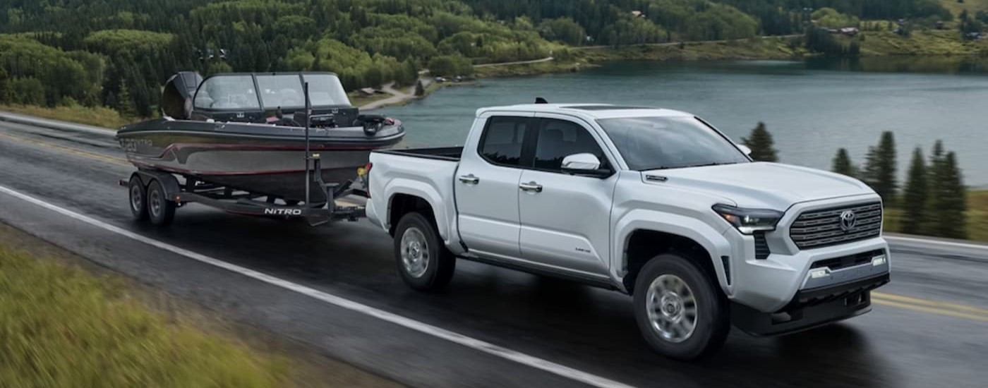 A white 2025 Toyota Tacoma for sale near Greenfield towing a trailer.