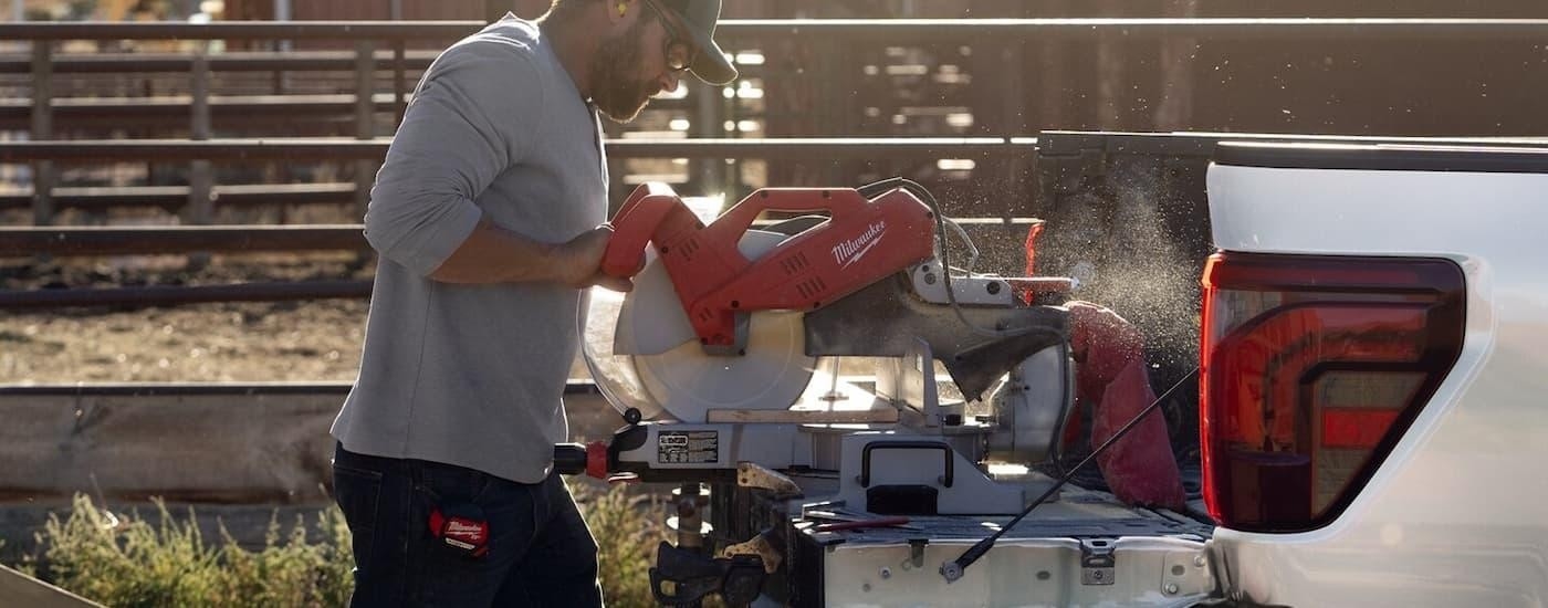 A man cutting wood on the back of a white 2025 Ford F-150.