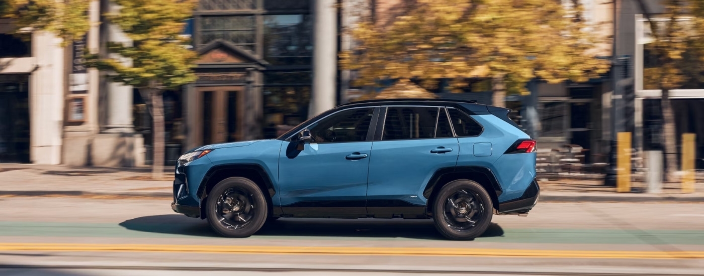 A blue 2025 Toyota RAV4 Hybrid for sale near Ardsley from the side.
