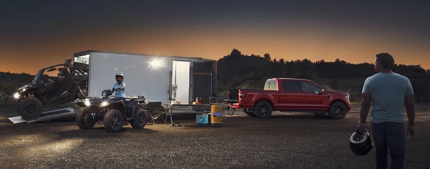 A red 2025 Ford F-150 for sale near Bennington unloading a trailer.