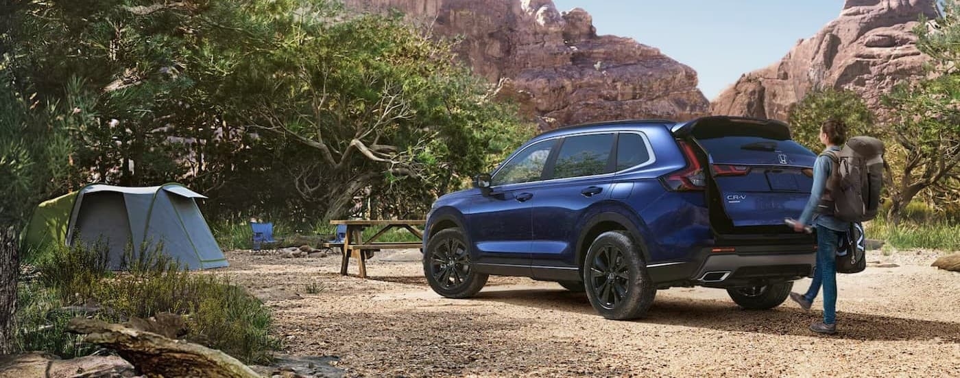 A blue 2025 Honda CR-V Sport Touring Hybrid parked on a campsite.
