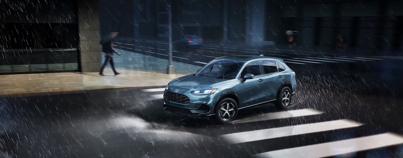 Blue 2025 Honda HR-V driving through a city in the rain