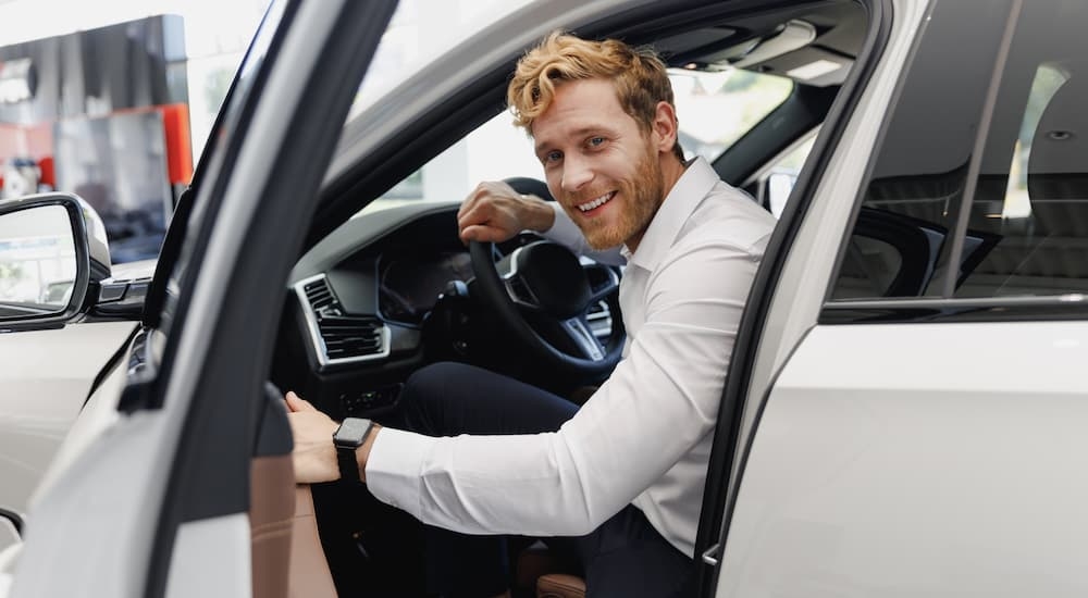 Man opening the driver's side door of a white vehicle