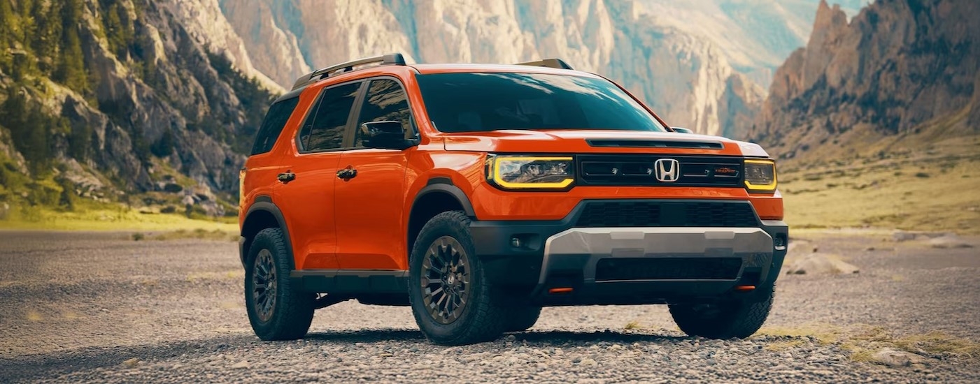 An orange 2026 Honda Passport TrailSport Elite parked off-road.