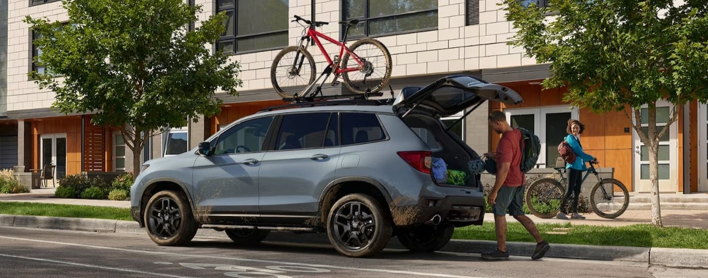 A blue 2024 Honda Passport parked in a city.