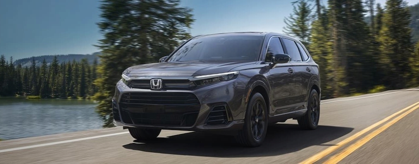 A gray 2025 Honda CR-V driving near a lake.