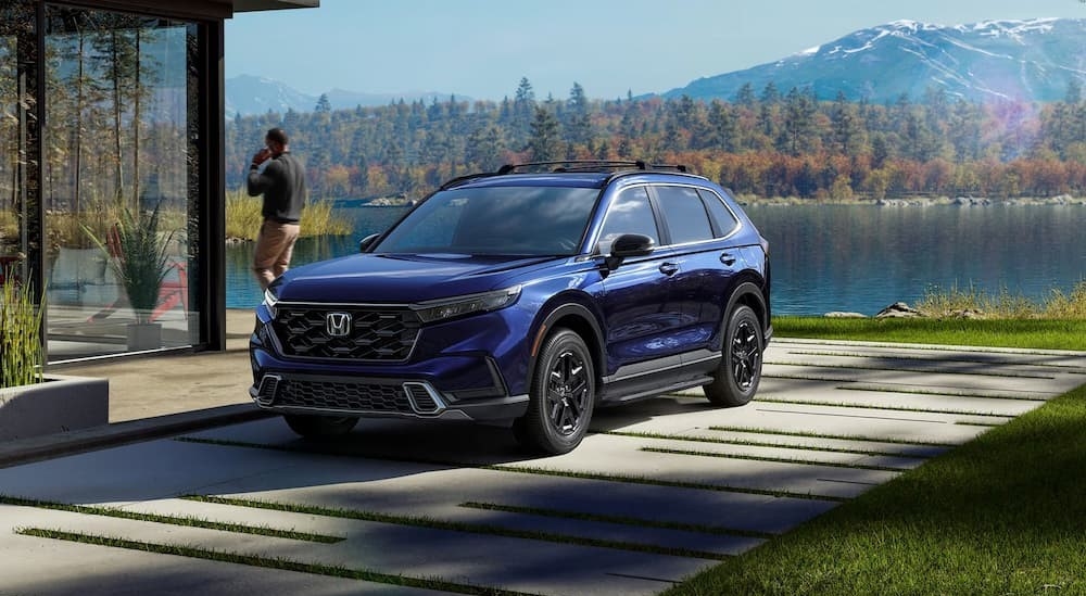 A blue 2026 Honda CR-V parked near a lake house.