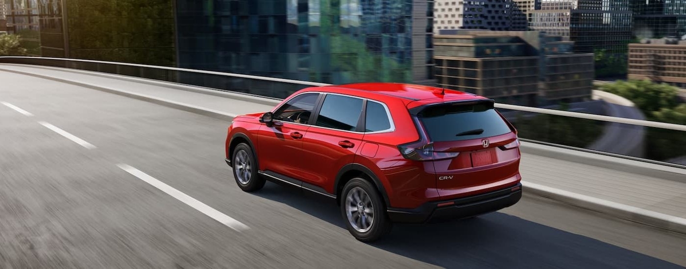 A red 2024 Honda CR-V driving on a bridge.