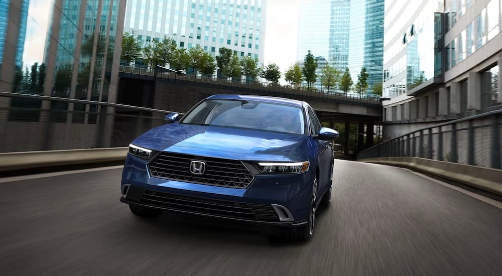 A blue 2023 Honda Accord driving on a city street.