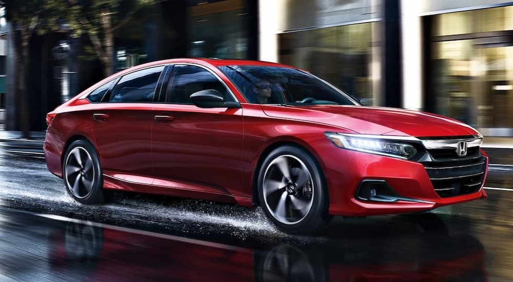 A red 2022 Honda Accord Sport driving on a wet city road.
