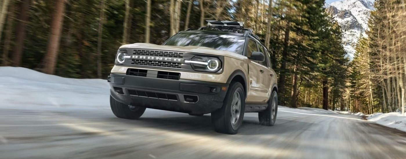 Tan 2025 Ford Bronco Sport for sale near Claremont driving through a forest.