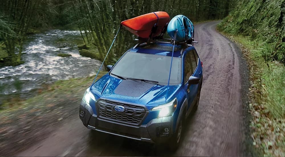 Blue 2025 Subaru Forester Wilderness driving by a river.