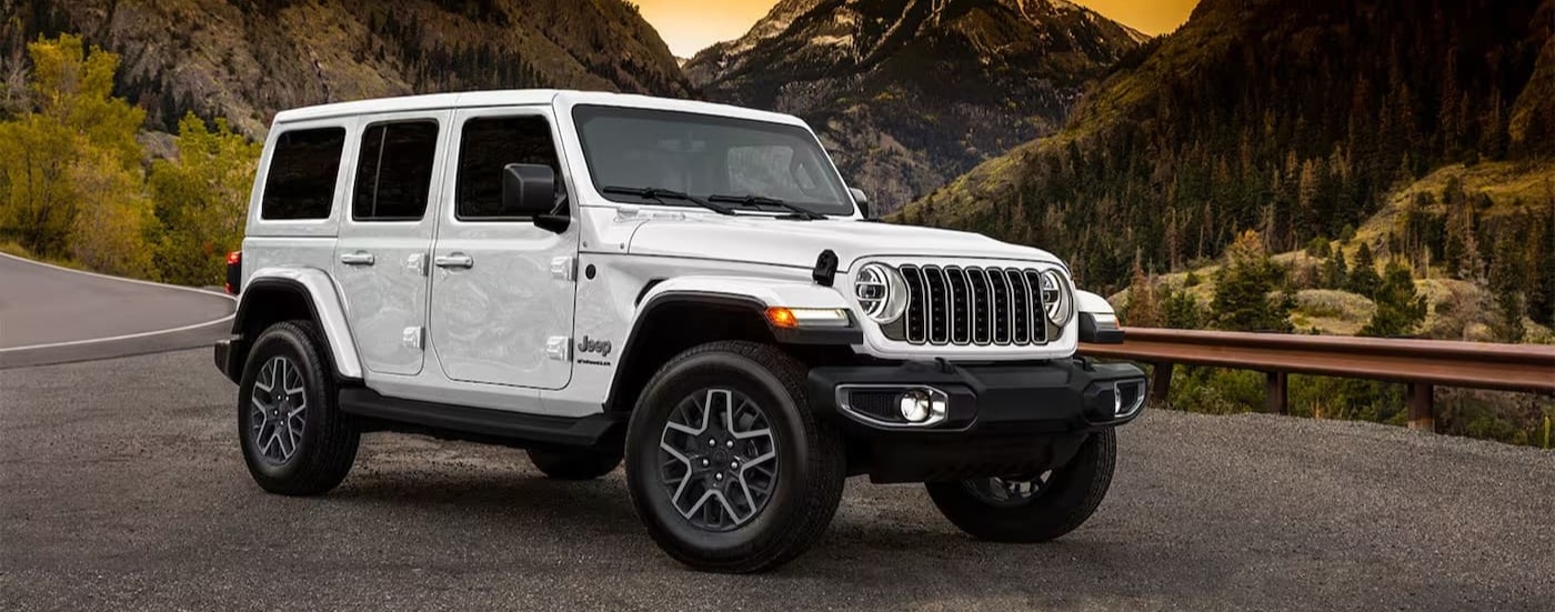 A white 2025 Jeep Wrangler parked on the side of a road.