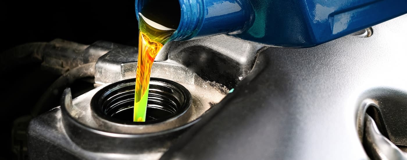 Oil pouring out of a blue bottle into an engine